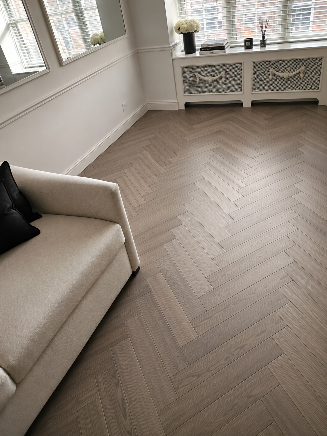Light oak herringbone hardwood flooring in a classic New York City apartment living room by FF Solutions